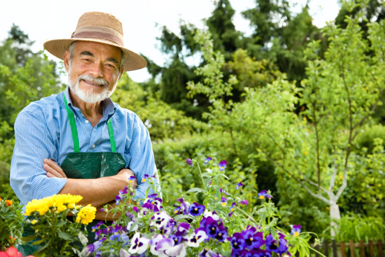 Gardener standing among colorful flowers in lush garden.