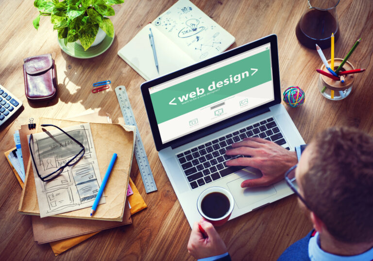 Person designing website on laptop with coffee cup