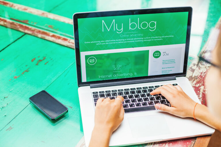 Person blogging on laptop with green screen.